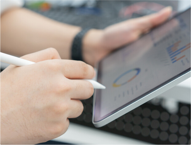 Close up of a person viewing charts and statistics on a tablet and working with an electronic pen.